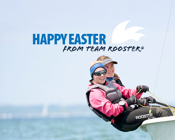 Two smiling sailors in Rooster-branded gear lean out of a sailboat on the water, with a clear sky and the text 'Happy Easter from Team Rooster®' above them.